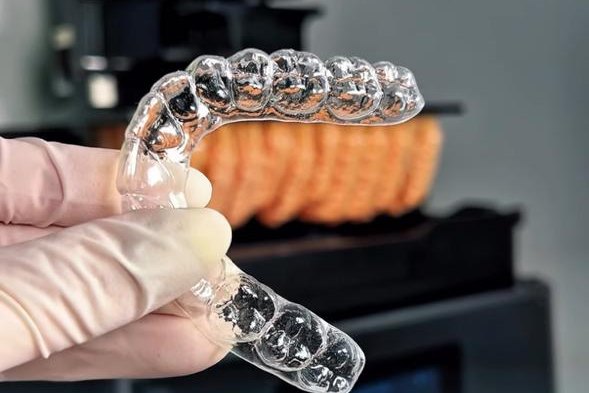 Alineador terminado, recortado y pulido, sostenido con guantes en el laboratorio